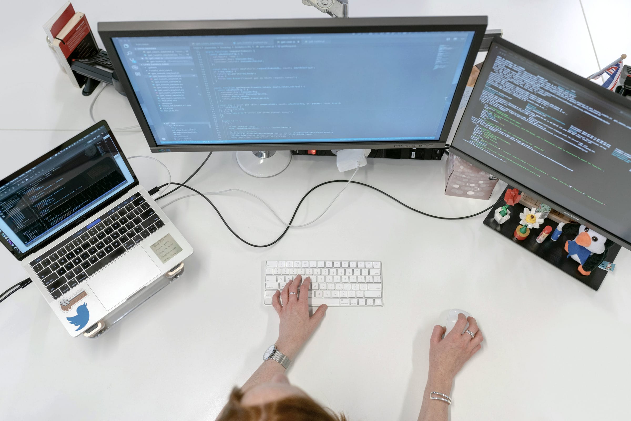 Overhead view of a developer’s desk with two monitors and a laptop.