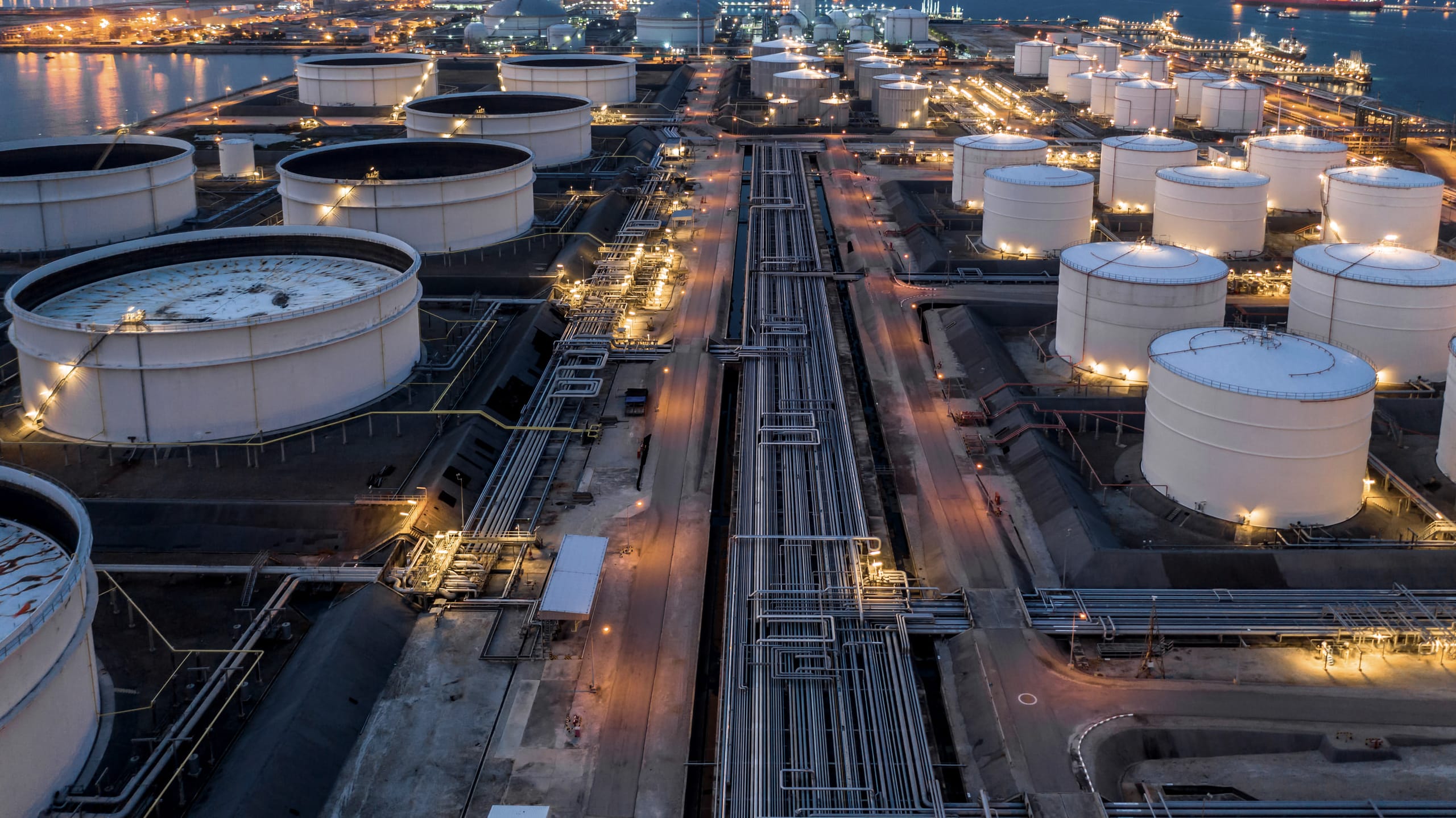 An oil and gas storage and processing facility seen from above at dusk.